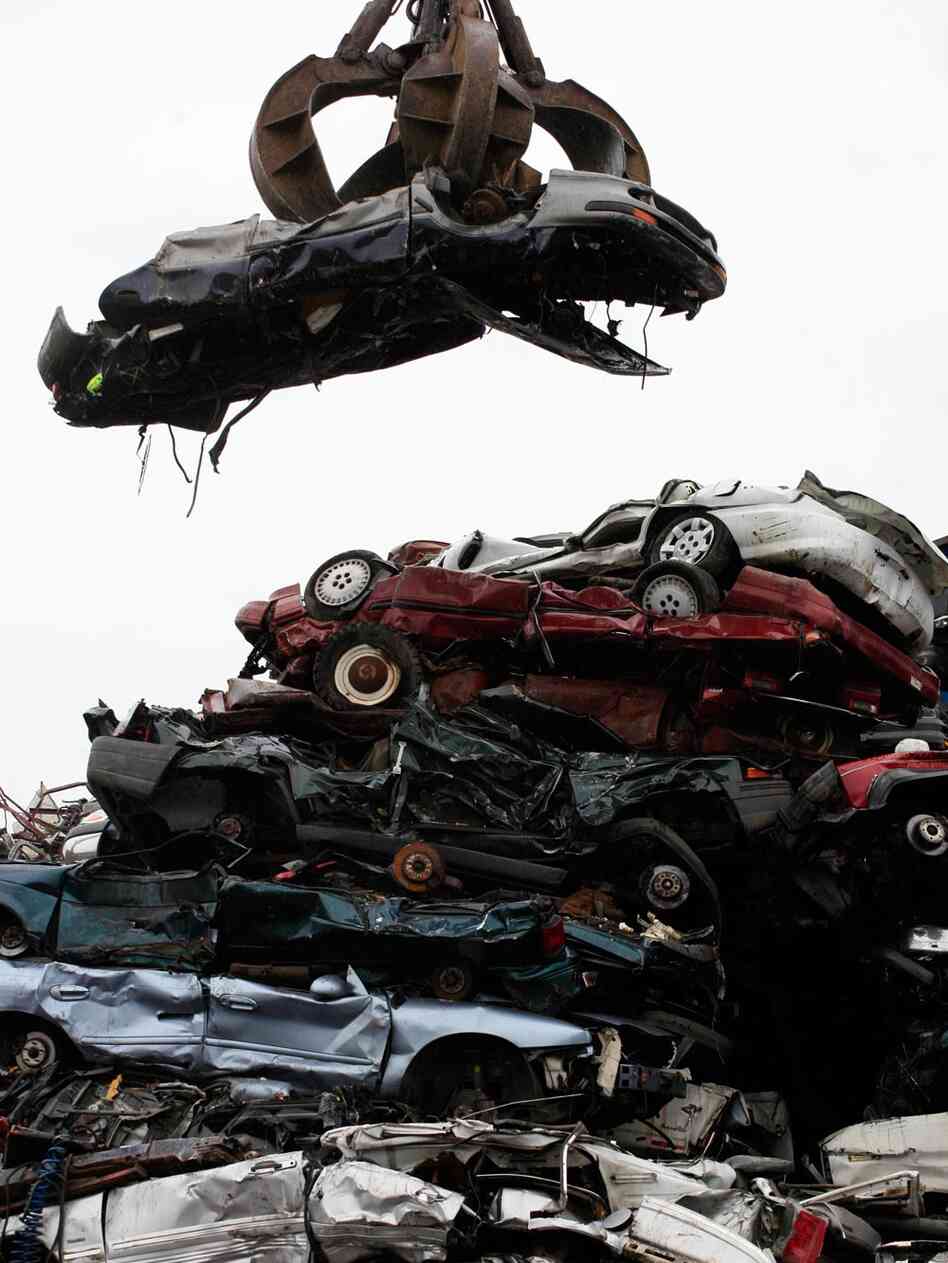 A car dangling over a wreckage yard. Mark Lennihan/AP