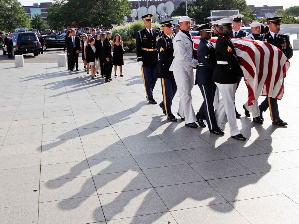 Family members follow an honor guard as members carry the casket of Sen. Edward Kennedy to the John F. Kennedy Presidential Library, in Boston on Thursday.