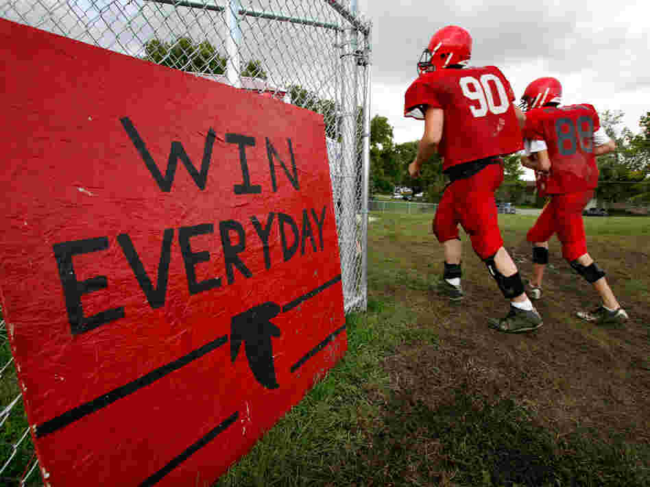 'Win Everyday': Aplington-Parkersburg High football players run past a sign on the practice field