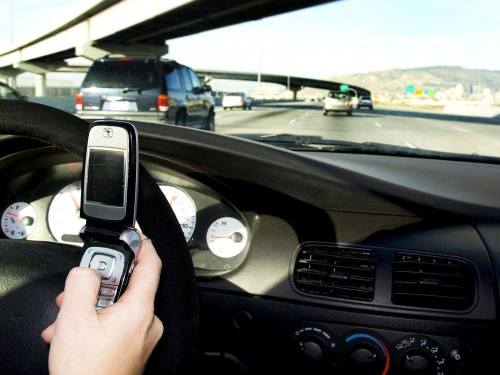 A person texts while driving on the freeway.