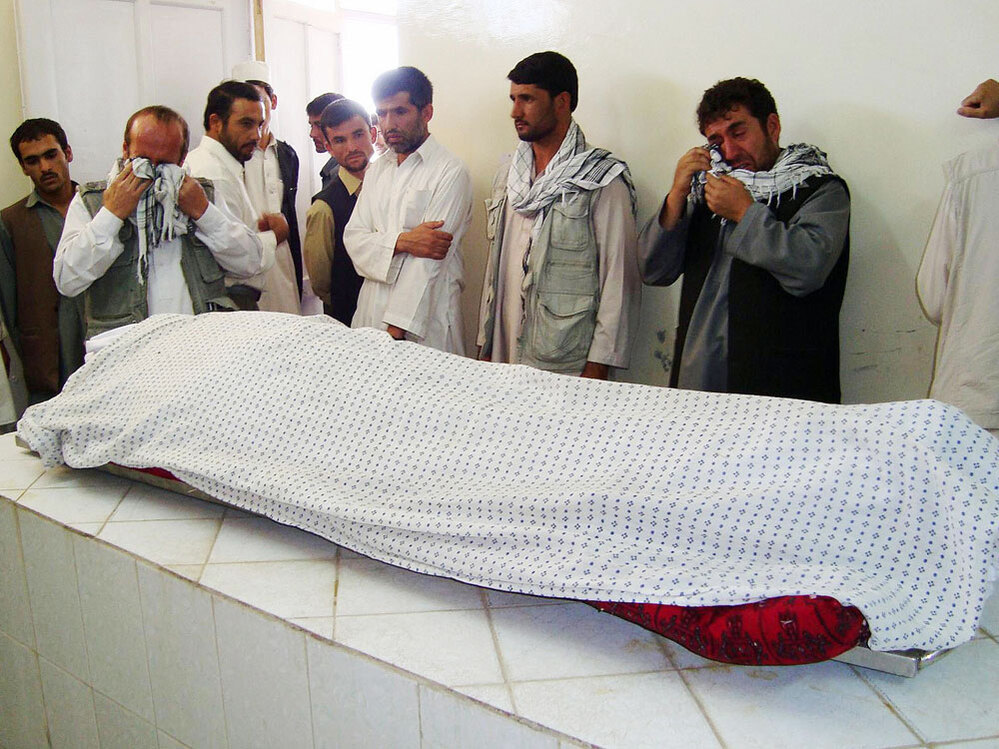 Men weep over the body of Afghan journalist  Sultan Munadi.