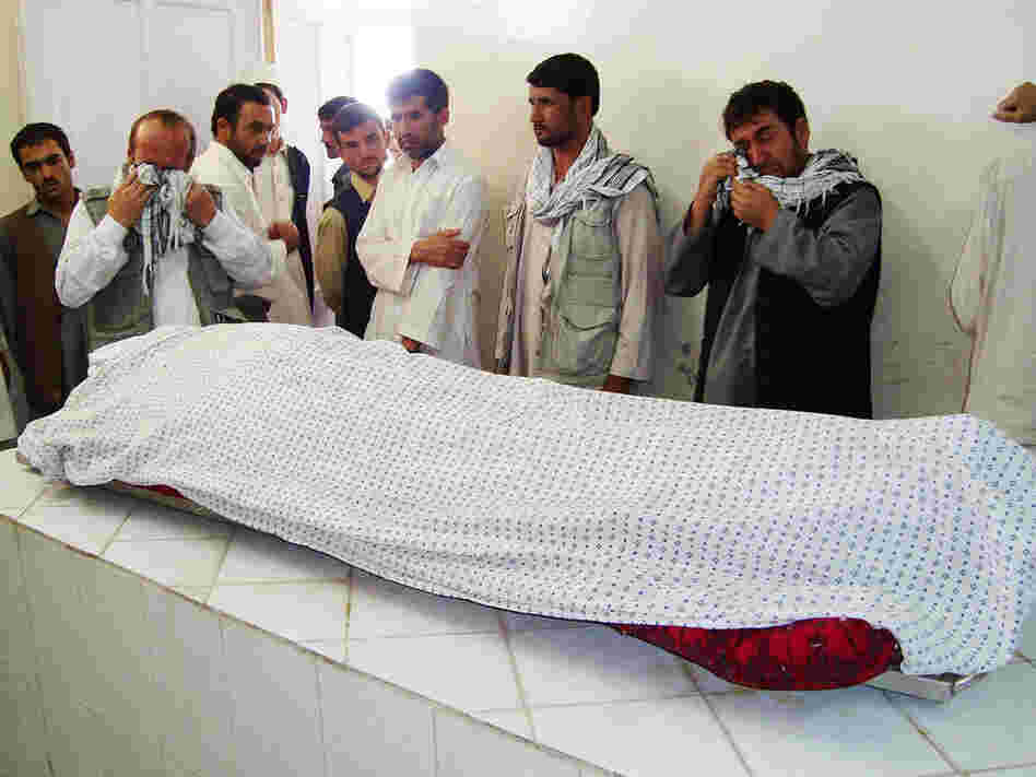 Men weep over the body of Afghan journalist  Sultan Munadi.