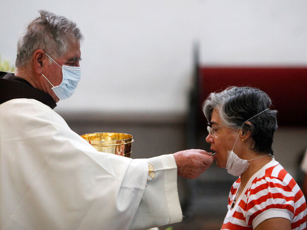 A priest, wearing a mask as a precaution against swine flu, gives Holy Communion to a parishioner