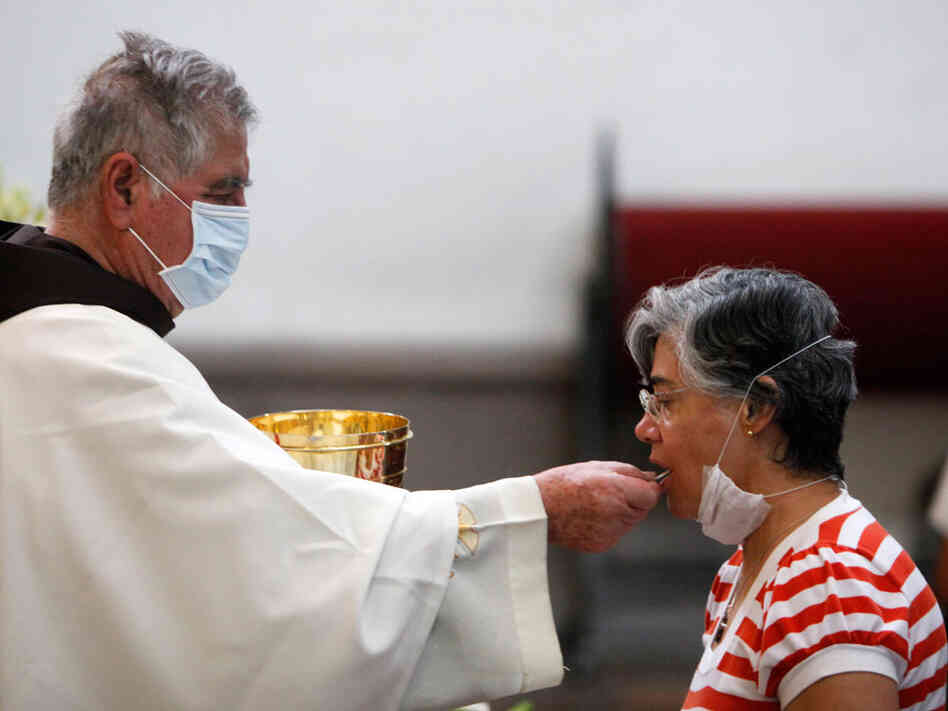 A priest, wearing a mask as a precaution against swine flu, gives Holy Communion to a parishioner