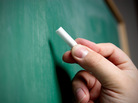 A hand poised to write on a chalkboard. A hand poised to write on a chalkboard.