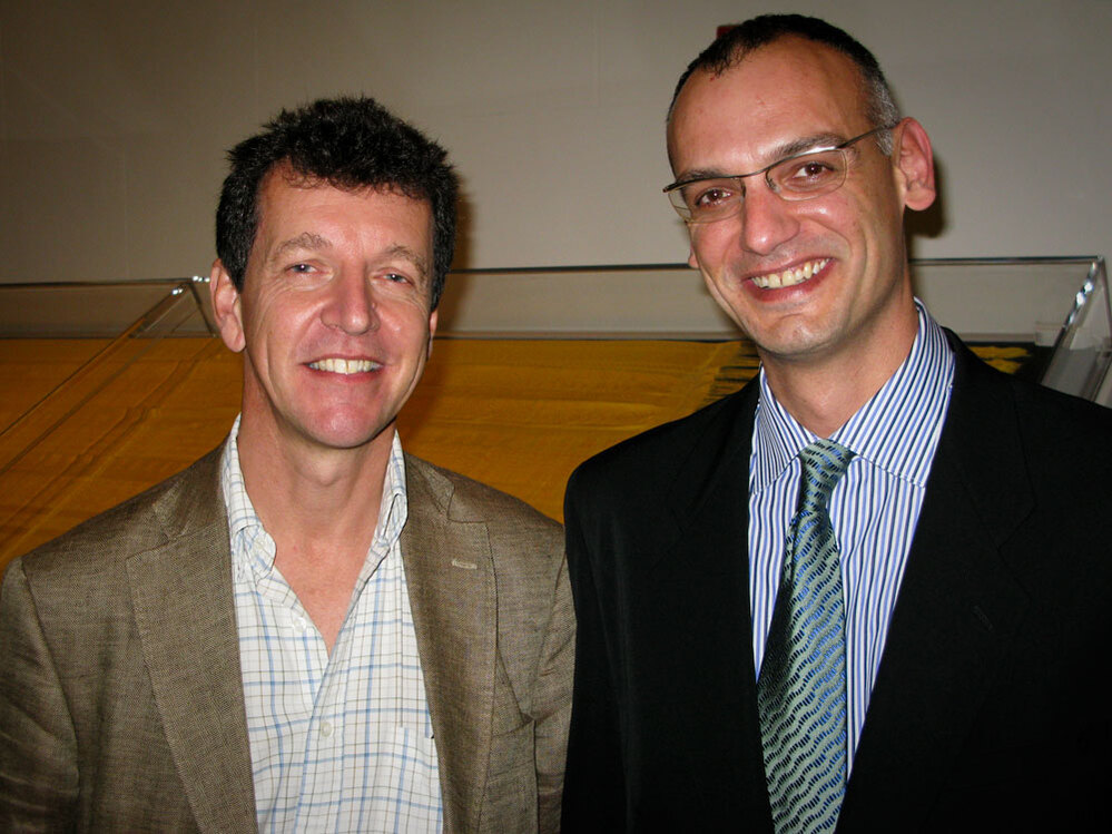 Simon Peers and Nicholas Godley stand in front of the gold tapestry.