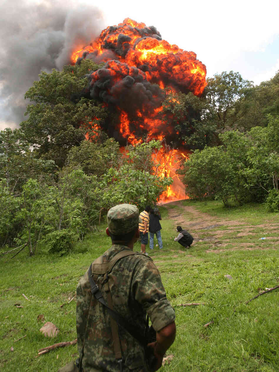 A soldier watches the burning of a clandestine methamphetamine laboratory.