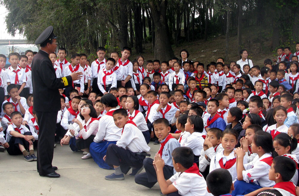 Schoolchildren listen to a lecture by one of the first North Koreans to board the USS Pueblo