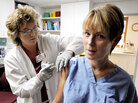 A nurse administers the H1N1 vaccine to a female patient A nurse administers the H1N1 vaccine to a female patient