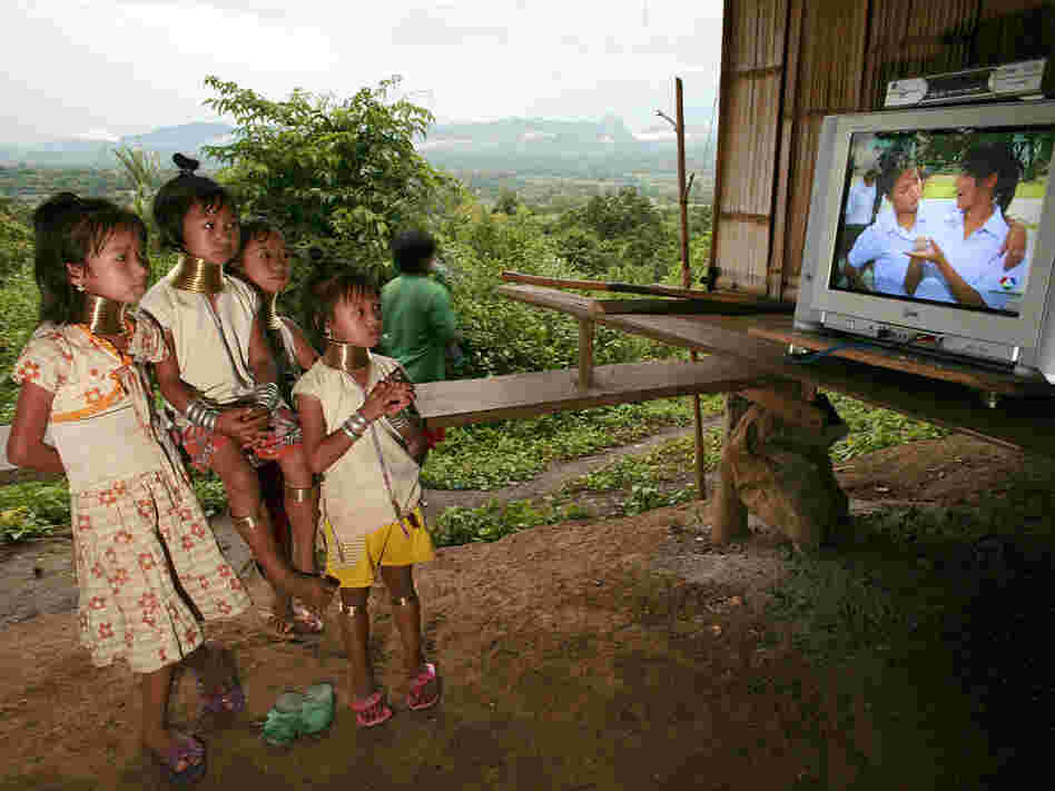 Young girls of the Long Neck Padaung hill tribe watch television in a small village in Chiang Dao, T