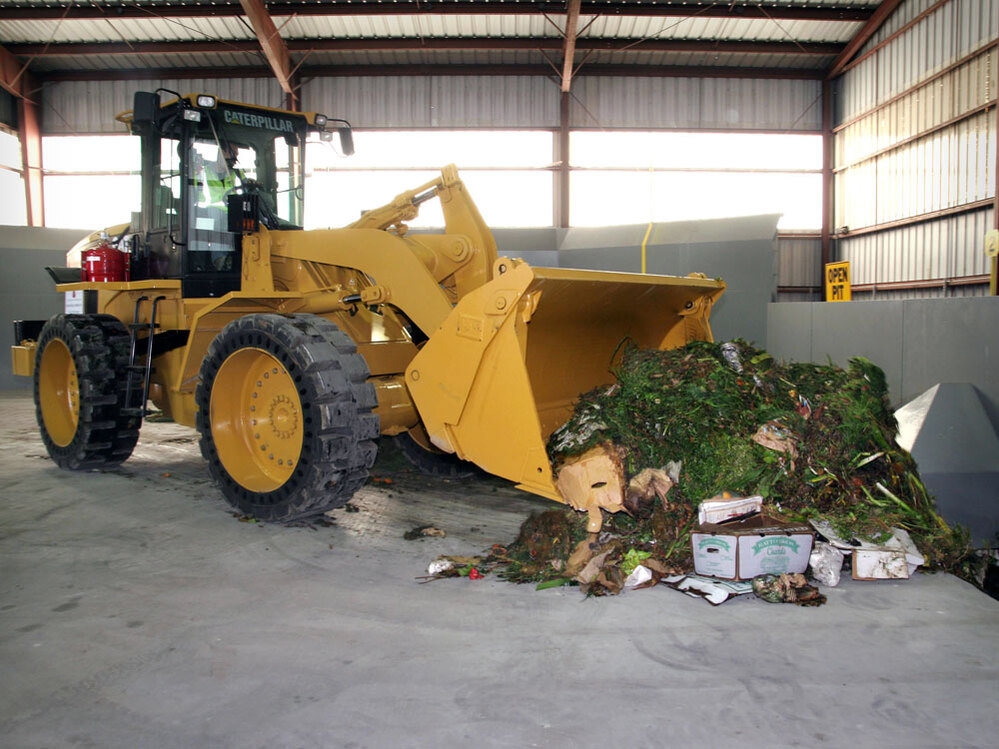 A front loader moves food waste in the Organics Annex.