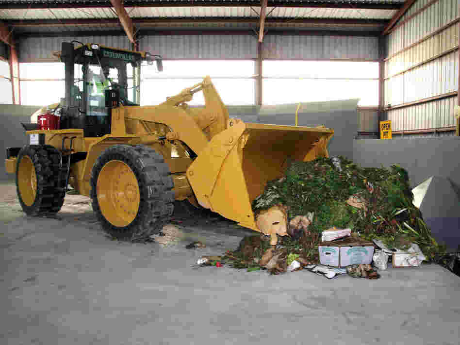 A front loader moves food waste in the Organics Annex.