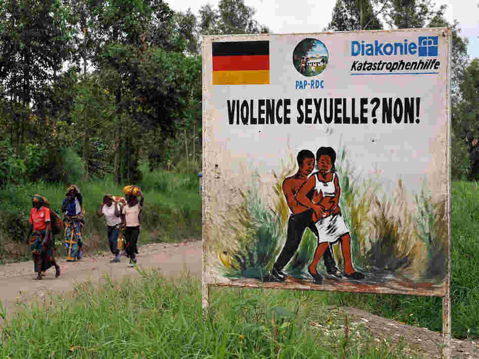 Congolese women walk past a sign opposing sexual violence in December 2008 in eastern Congo