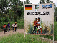 Congolese women walk past a sign opposing sexual violence in December 2008 in eastern Congo. But efforts by international authorities to stamp out the scourge face many obstacles.