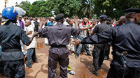 Police control the crowd as they react before looking for the bodies of family members and friends that were killed during a rally.