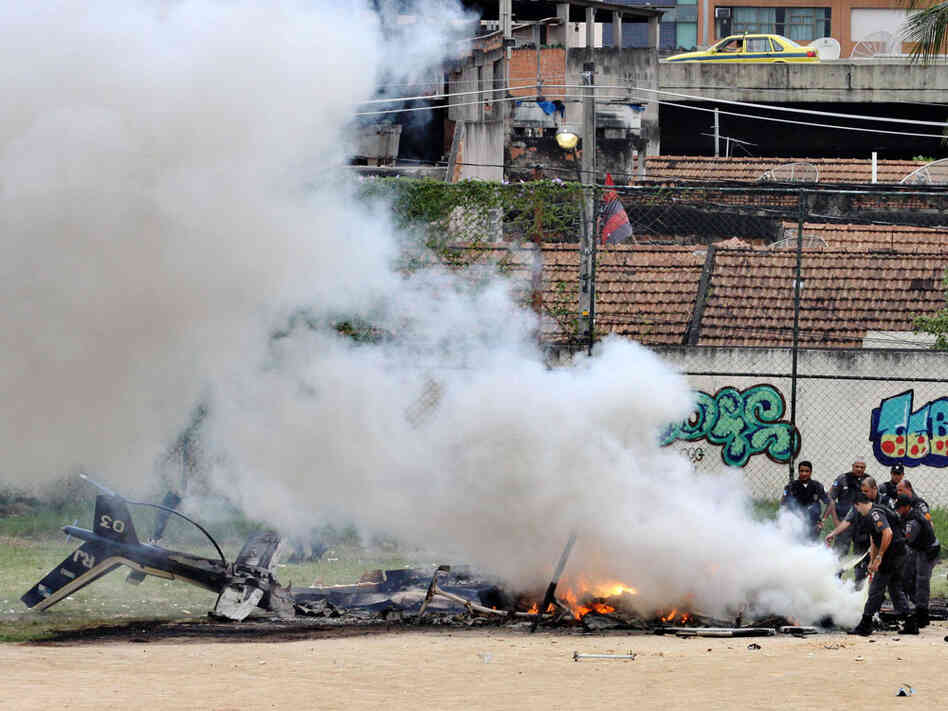 Police officers extinguish a fire from the wreckage of a police helicopter in Morro de Macacos slum.