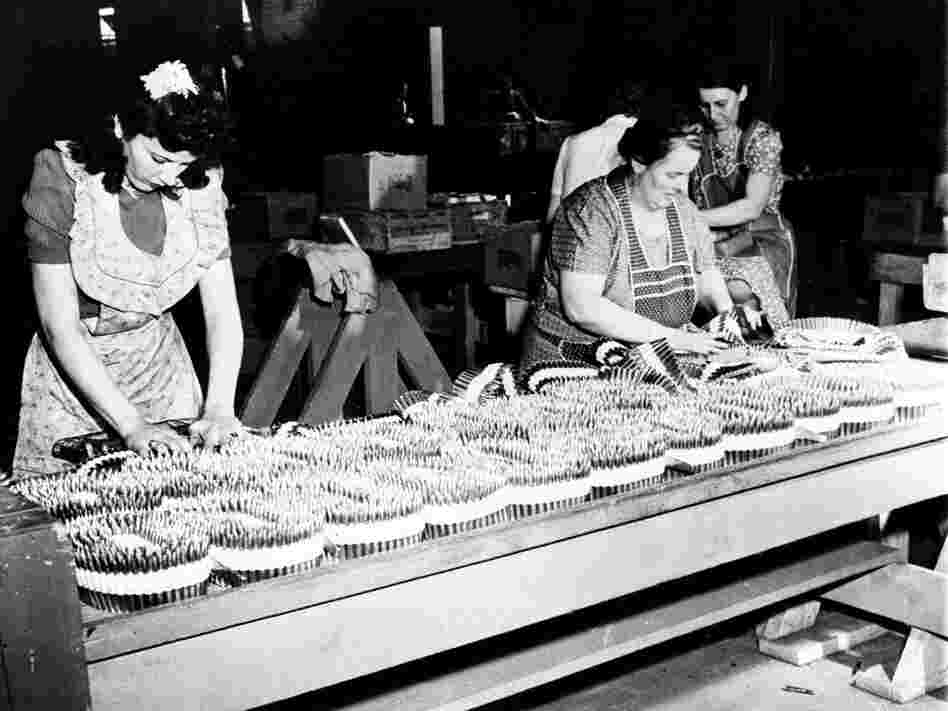 Women pack bullets into machine gun belts during World War II.