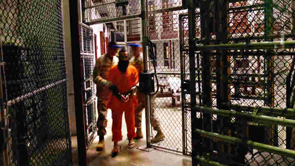 A wide view of a 'noncompliant' detainee escorted by guards at Guantanamo Bay