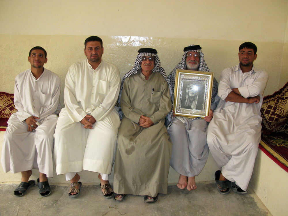 Dakhil Shakir holds a photograph of his father alongside his sons and brother.