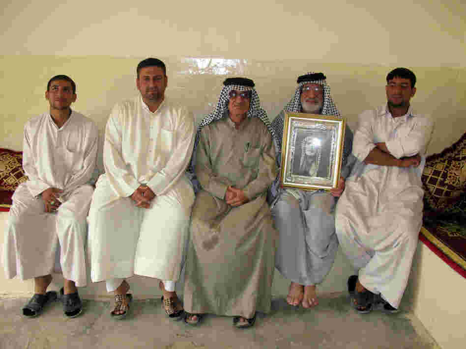 Dakhil Shakir holds a photograph of his father alongside his sons and brother.