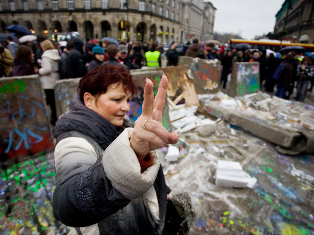 WIDE: A Polish woman flashes the victory sign near a replica of the destroyed Berlin Wall in Warsaw