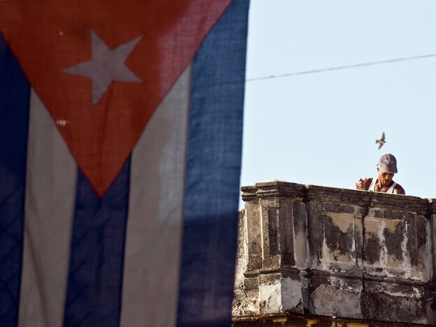 A Cuban works next to a national flag in Havana in August.
