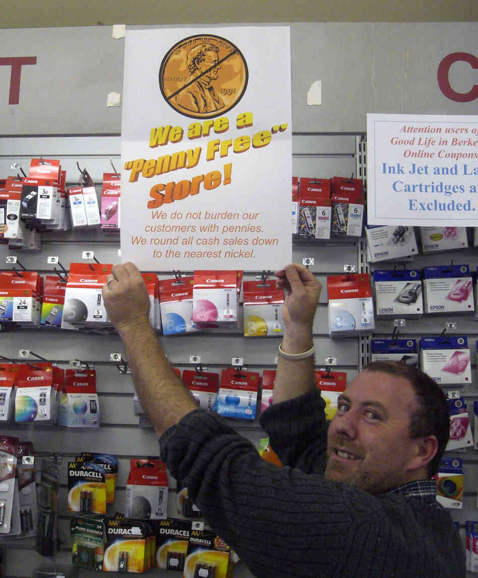 Cashier Andrew Allen stands with his store's 'No Penny' sign.