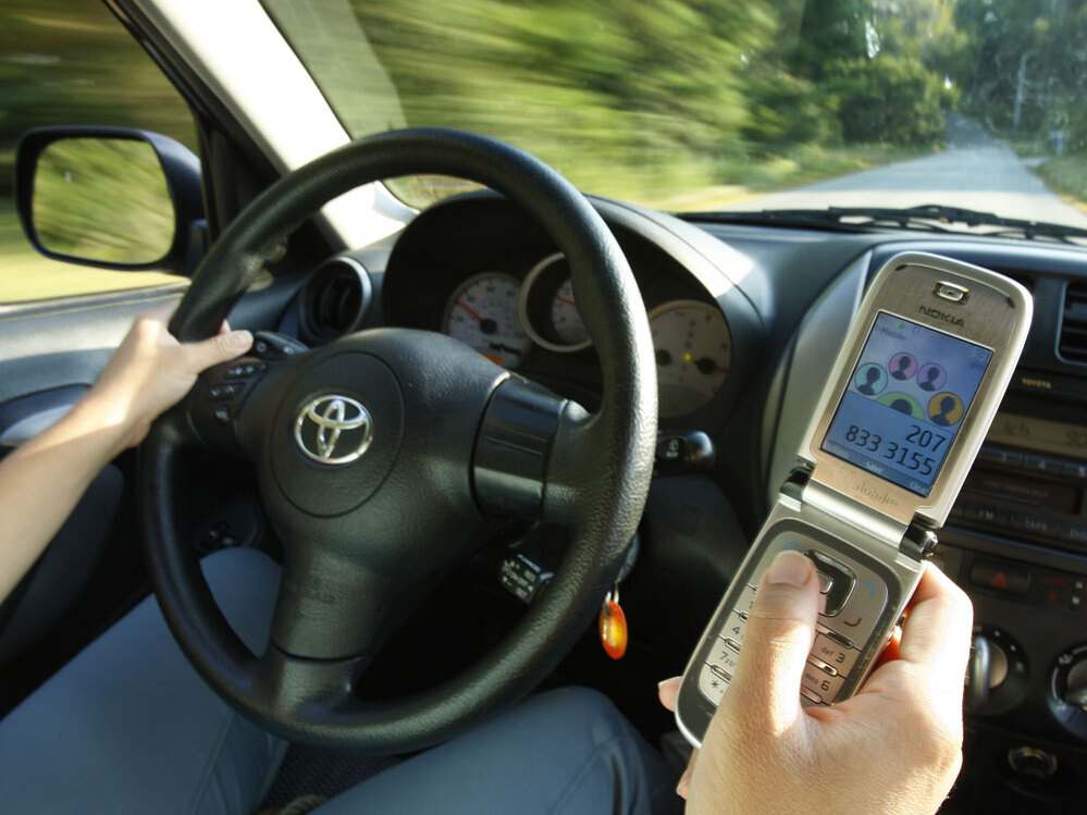 A driver uses a cell phone in Freeport, Maine.