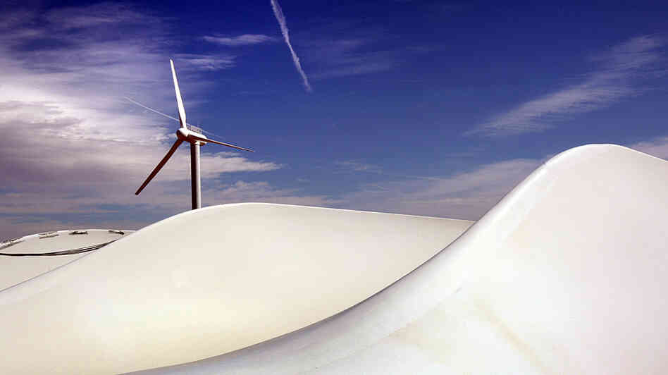 A wind turbine turns as giant blades lie awaiting new construction at NREL. A wind turbine turns as giant blades lie awaiting new construction at NREL.