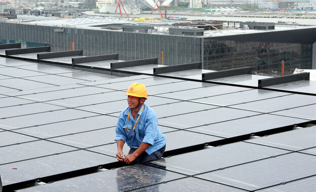 A Chinese worker installs solar panels on the rooftop