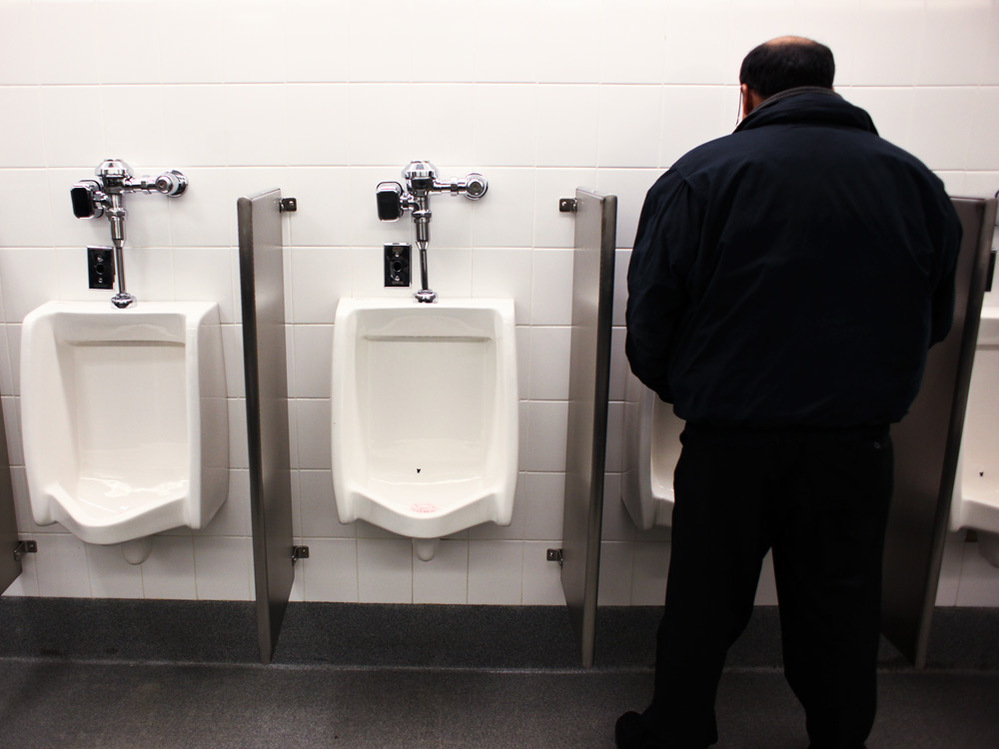 Man at urinal in JFK airport.