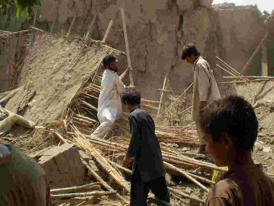 Pakistani villagers gather at the rubble of houses belonging to supporters of Baitullah Mehsud.