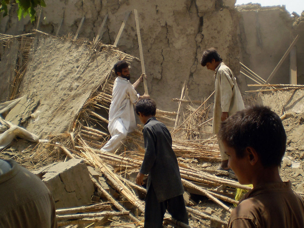 Pakistani villagers gather at the rubble of houses belonging to supporters of Baitullah Mehsud.