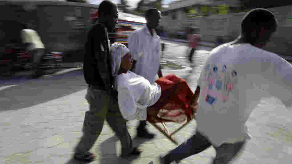 A woman is carried in a chair amidst destruction from the earthquake in Port-au-Prince.