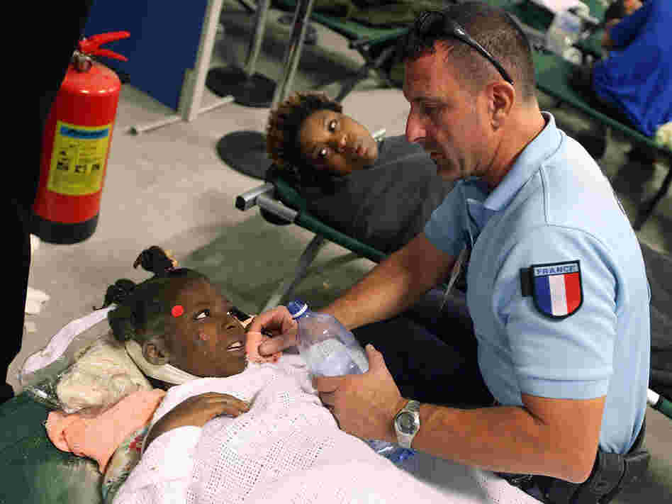 A girl is given water by a French aid worker at a makeshift field hospital in Port-au-Prince.