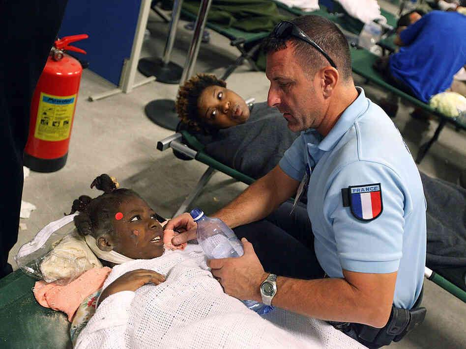An injured girl is given water by a French aid worker An injured girl is given water by a French aid worker