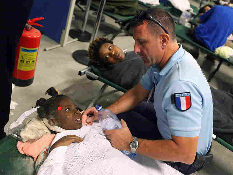 An injured girl is given water by a French aid worker An injured girl is given water by a French aid worker