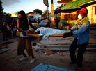 Haitian men carry the body of a child to a dump truck Haitian men carry the body of a child to a dump truck