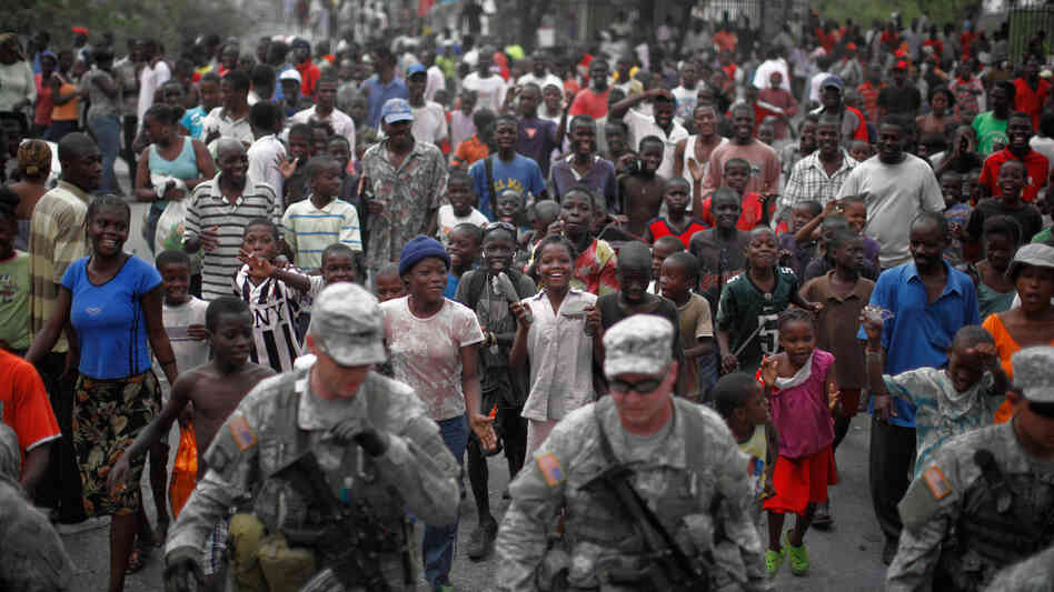 Haitians follow soldiers with the 82nd Airborne division through a street in Port-au-Prince. Haitians follow soldiers with the 82nd Airborne division through a street in Port-au-Prince.