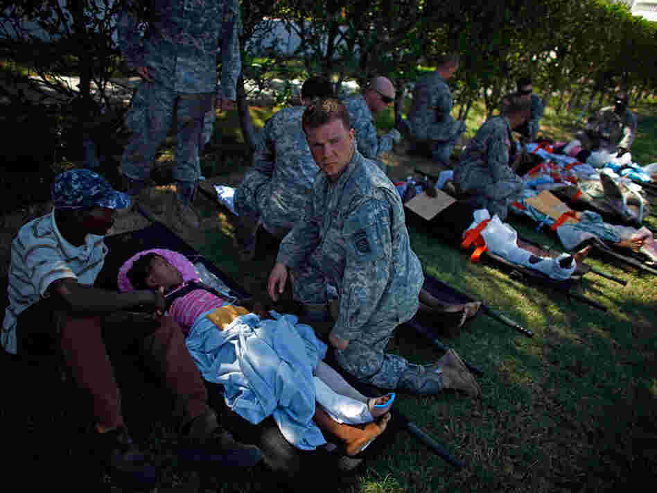 U.S. soldiers watch over patients in a staging area in front of the National Palace. U.S. soldiers watch over patients in a staging area in front of the National Palace.