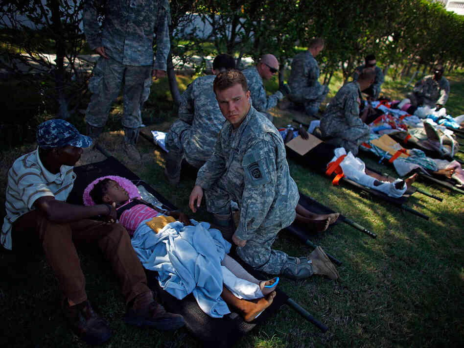 U.S. soldiers watch over patients in a staging area in front of the National Palace. U.S. soldiers watch over patients in a staging area in front of the National Palace.