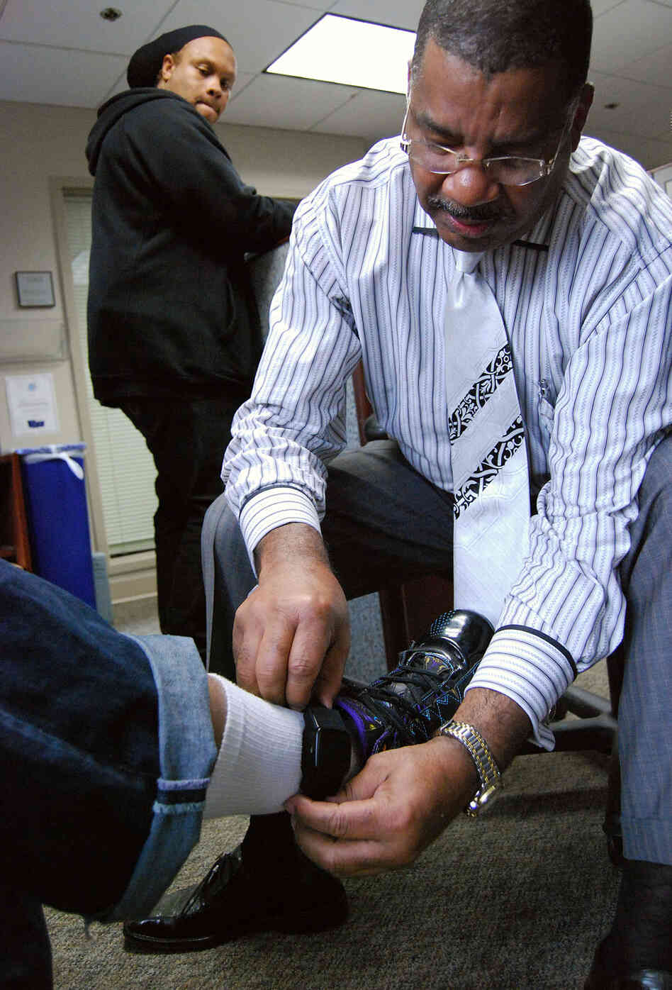 A program manager for the D.C. Pretrial Services Agency adjusts a defendant's ankle bracelet. A program manager for the D.C. Pretrial Services Agency adjusts a defendant's ankle bracelet.