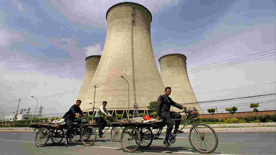 Workers in China bicycle past cooling towers of a coal-fired power plant. Workers in China bicycle past cooling towers of a coal-fired power plant.