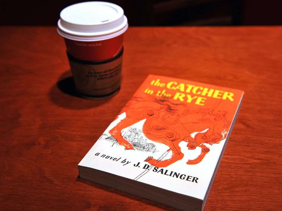 A copy of 'The Catcher in the Rye' next to a cup of coffee