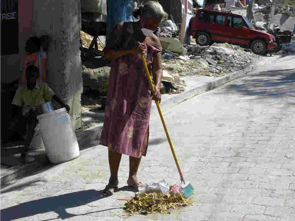 Lunide Francillon sweeps the street to make a little money.