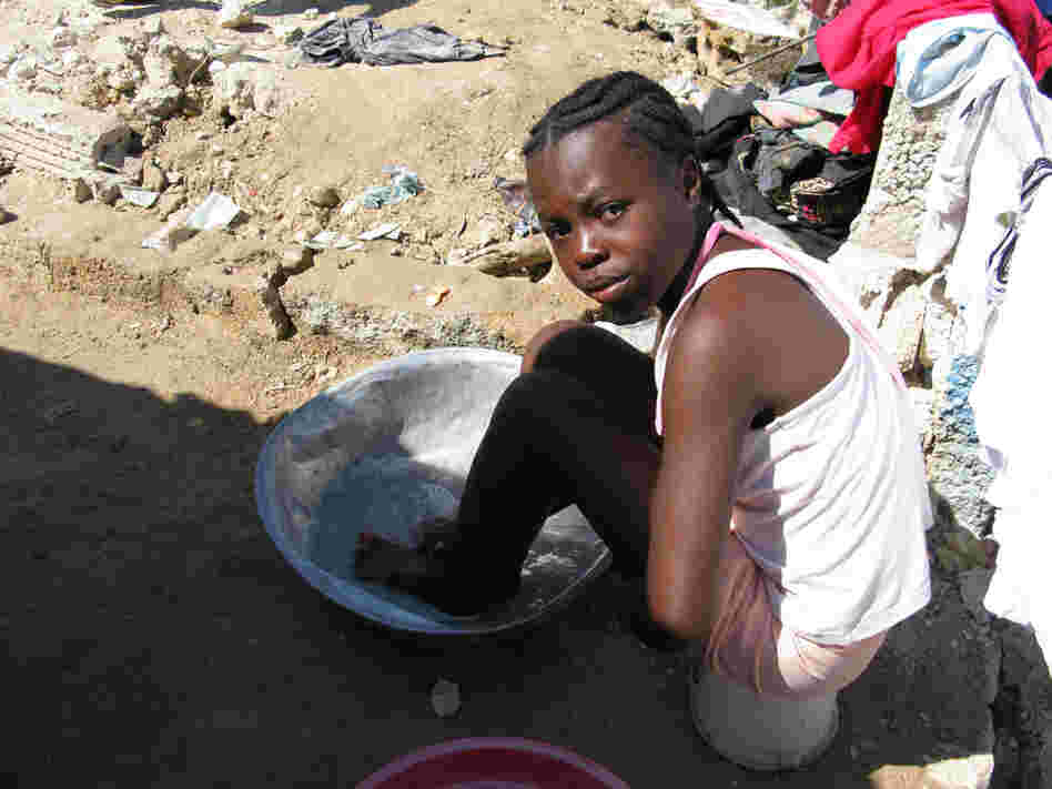 A little girl washes herself with soapy water in an encampment built by survivors in Haiti.