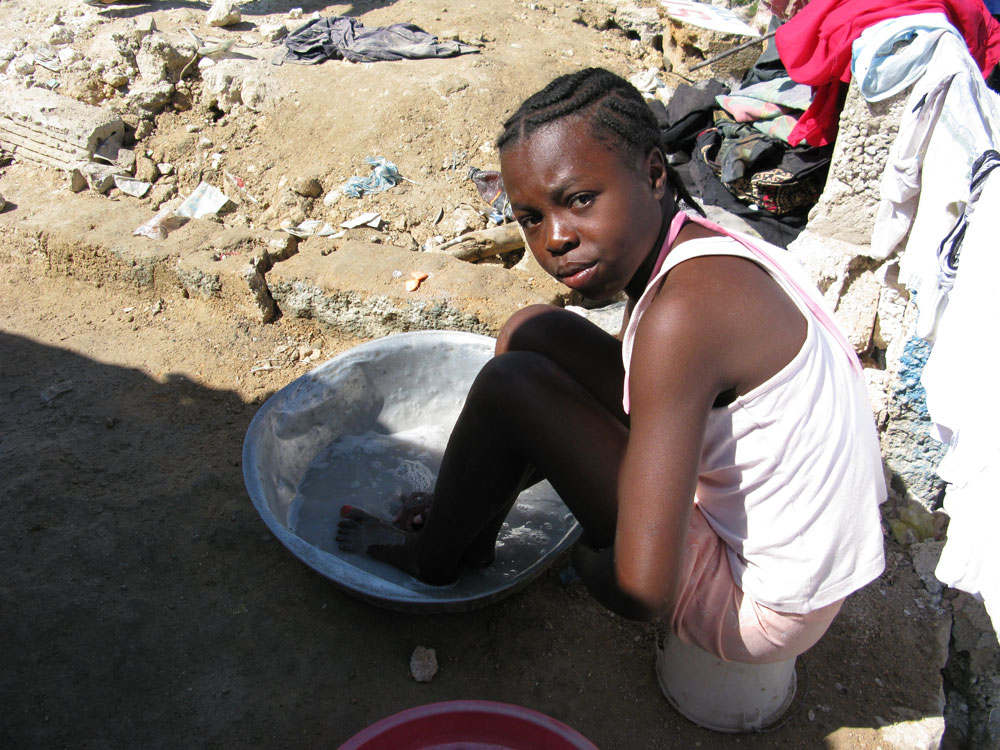 A little girl washes herself with soapy water in an encampment built by survivors in Haiti.
