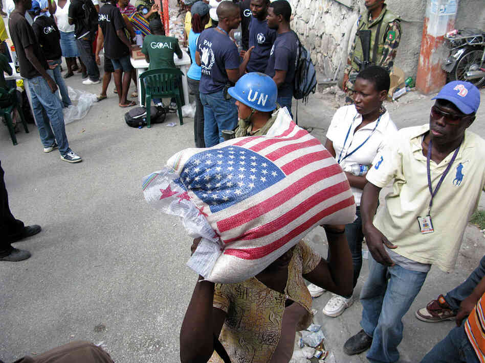 A woman carries off a 55-pound sack of rice given out in Port-au-Prince, Haiti, on Sunday.