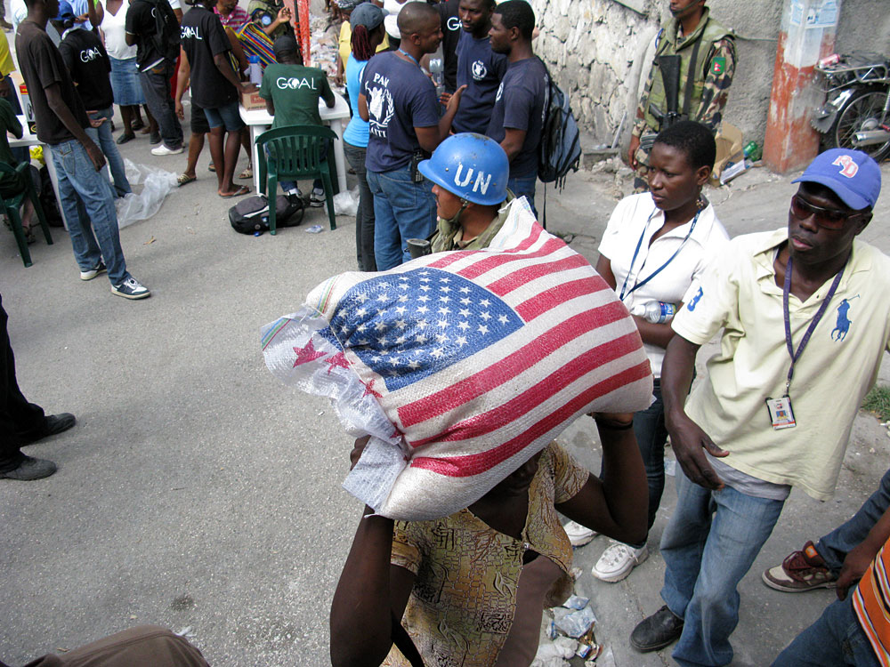 A woman carries off a 55-pound sack of rice given out in Port-au-Prince, Haiti, on Sunday.