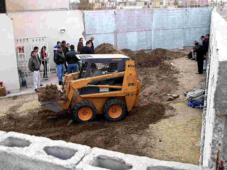 Members of the Federal Agency of Investigations excavate the yard at the House of Death.